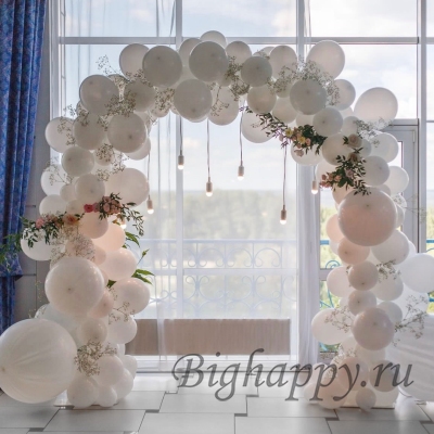 Белая арка из шаров разного размера с искусственными цветами фото